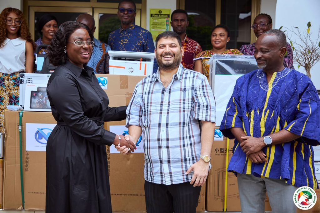 Representatives of Nilex Corp and the Ghana Medical Trust Fund shaking hands beside donated medical equipment